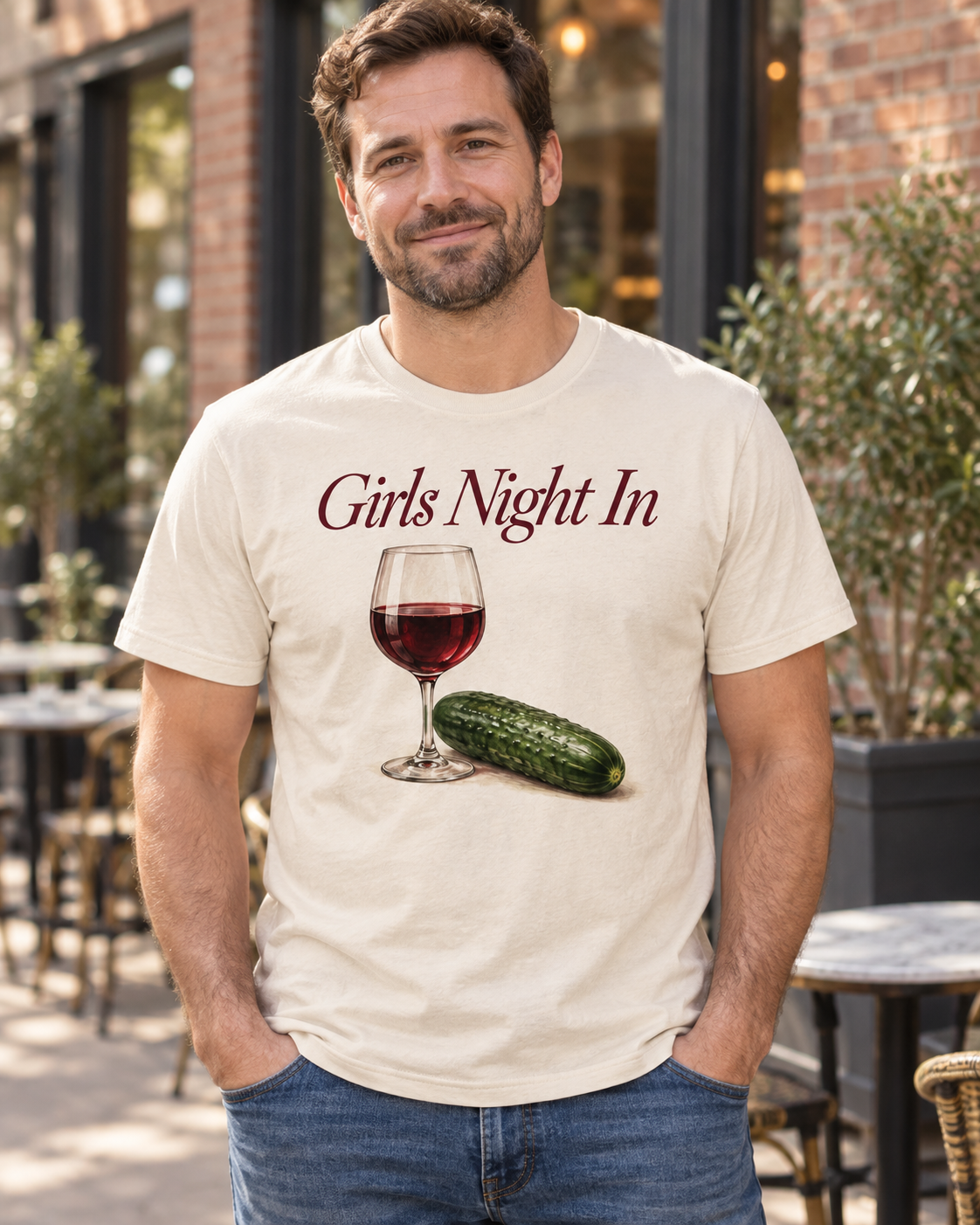 A smiling man wearing the cream Girls Night In shirt with a wine glass and cucumber
